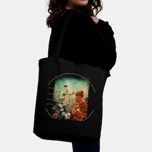 Könnte beinhalten: Schwarze Tragetasche mit einer farbenfrohen Illustration einer Person in einem Blumenfeld. Das Kunstwerk ist von einem goldenen Kreis umrahmt. Die Tasche hat ein schlichtes Design mit einem schwarzen Schulterriemen.