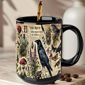 Könnte beinhalten: Schwarze Kaffeetasse mit schwarzem Henkel. Die Tasse hat ein Vintage-Design mit einem Raben, Schmetterlingen, Pilzen und dem Text "crow murder hiding magical objects in the wildflowers."