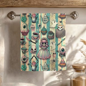 May include: A decorative Halloween-themed towel with a repeating pattern of spooky illustrations. The design includes ghosts, skulls, teacups, cupcakes, and a doll, set against a striped background in teal, beige, and pink.