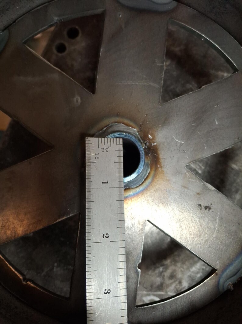 May include: Close-up of a metal disc with six cutouts, a ruler measuring 3 inches, and a circular hole in the center.