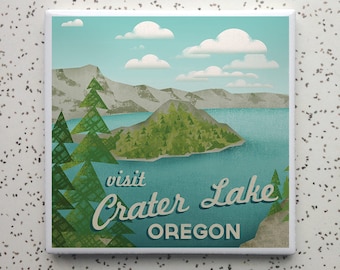 May include: Square ceramic tile with a vintage travel poster design. The artwork shows Crater Lake in Oregon, with the text "Visit Crater Lake Oregon." The scene includes a lake, mountains, trees, and clouds, in a retro style.