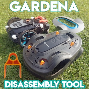 Puede incluir: Una herramienta de plástico negra y naranja para desmontar una cortadora de césped robótica. La herramienta tiene forma de gancho y tiene un agujero en la parte superior. La cortadora de césped está en el fondo, parcialmente visible.