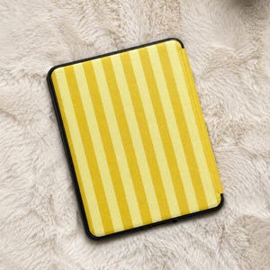 May include: A rectangular e-reader case featuring a vertical striped pattern in alternating shades of bright yellow and pale yellow. The case has a solid black frame surrounding the striped front panel, which is oriented vertically in the center.