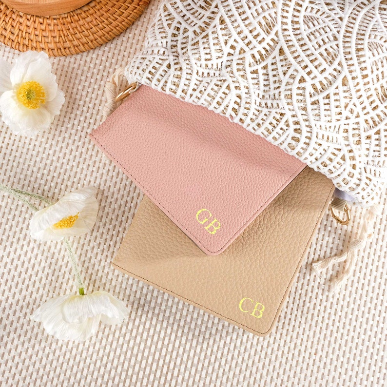 May include: Two leather pouches with gold lettering. The top pouch is pink and the bottom pouch is beige. Both pouches have the initials "CB" embossed on them.