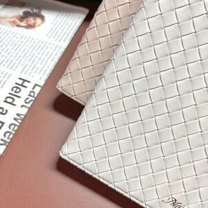 Puede incluir: Dos carteras de cuero trenzado, una de color beige claro y la otra blanca. La cartera blanca tiene la palabra "Moylite" grabada en la esquina inferior derecha.