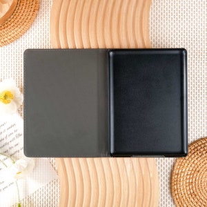 May include: A gray and black e-reader case with a textured cover and a black screen. The case is open and the screen is visible.