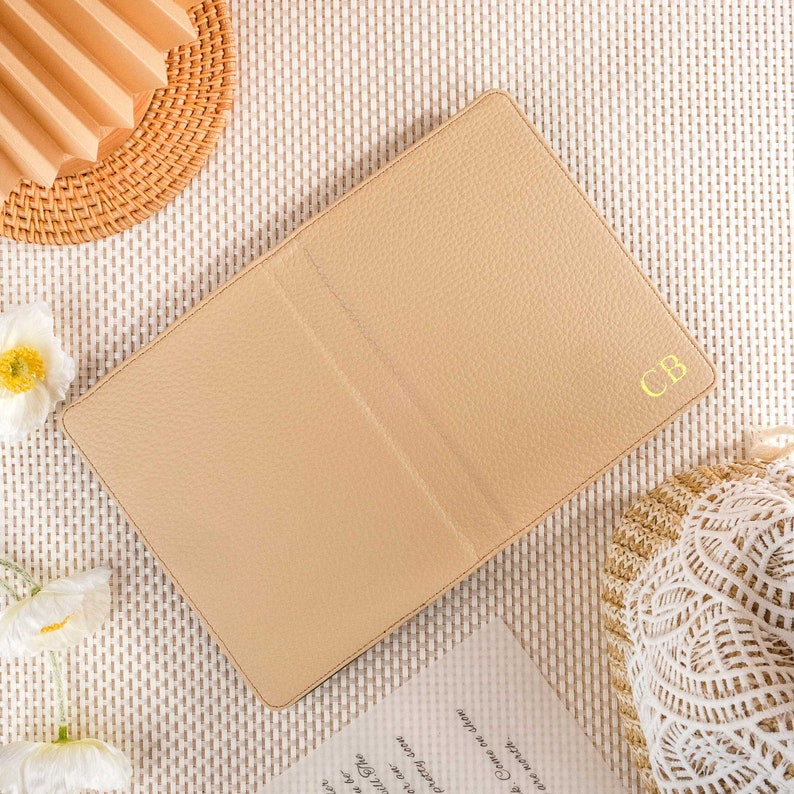 May include: A beige leather journal with the initials "CB" embossed in gold on the front cover.