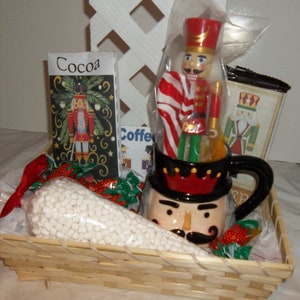May include: A wicker basket filled with a variety of Christmas themed gifts. The basket includes a mug with a nutcracker face, a bag of marshmallows, a box of cocoa mix, a box of coffee, and a nutcracker figurine.