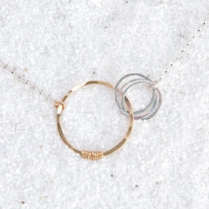 May include: A silver chain necklace with a gold circle pendant and three smaller silver circles attached to the pendant.