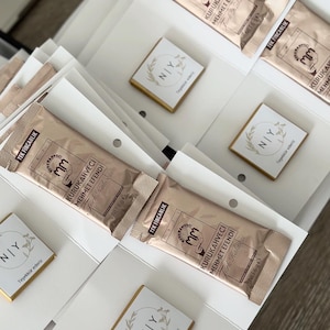 May include: A collection of rectangular Kurukahveci Mehmet Efendi Turkish coffee packets in metallic gold packaging, each labeled 6g, alongside small square white cards featuring a circular wreath graphic and the text NIY Teşekk&uuml;r ederiz.