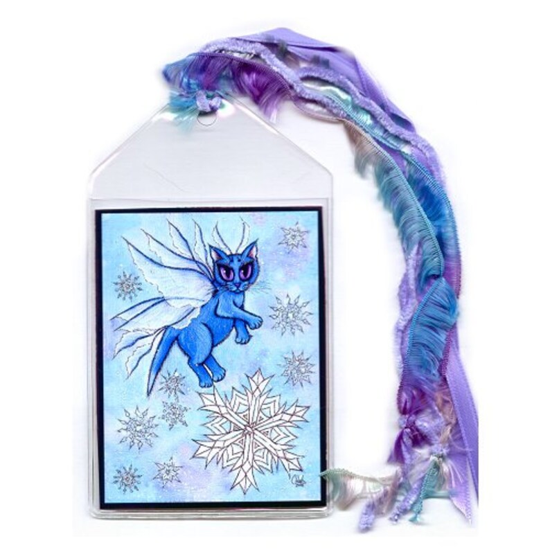 May include: A bookmark featuring a blue cat with fairy wings, surrounded by snowflakes, on a watercolor background. The bookmark has a clear plastic sleeve and is adorned with a flowing ribbon in shades of purple and blue.