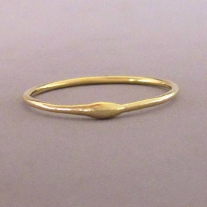 Puede incluir: Un anillo de banda de oro simple con una superficie ligeramente redondeada y texturizada.