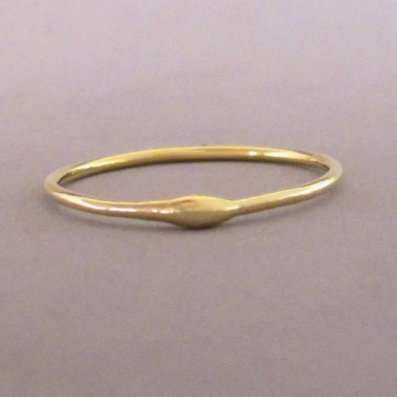 Puede incluir: Un anillo de banda de oro simple con una superficie ligeramente redondeada y texturizada.