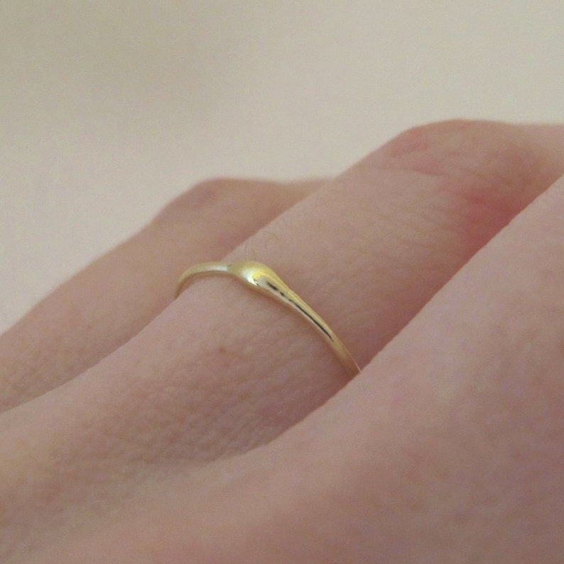 Puede incluir: Un fino anillo de banda de oro con una forma ligeramente curvada e irregular.