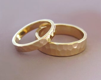 May include: Two gold hammered wedding bands, one slightly larger than the other, are intertwined.