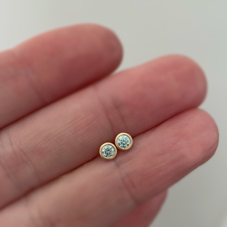 May include: A pair of gold stud earrings with small round clear gemstones.