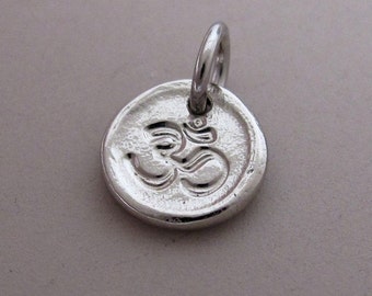 May include: Silver charm with an Om symbol engraved on a round disc.