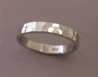 May include: A silver hammered band ring with the inscription "ES MK" on the inside.