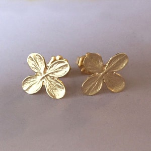 Peut inclure: Une paire de boucles d'oreilles dorées en forme de trèfles à quatre feuilles. Les boucles d'oreilles sont petites et délicates, et elles seraient un excellent cadeau pour une personne spéciale.