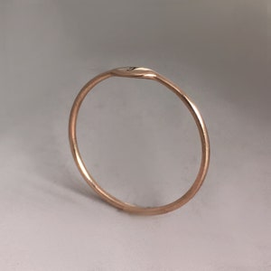 May include: A simple gold ring with a slightly curved top. The ring is smooth and has a subtle shine.