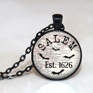 May include: A black necklace with a round glass pendant featuring a vintage map of Salem, Massachusetts. The map includes the text "SALEM Est. 1626" and several black bats.
