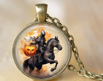 May include: A round pendant necklace with a bronze-colored chain. The pendant features a watercolor illustration of the Headless Horseman riding a black horse and holding a jack-o'-lantern. The background has orange and yellow hues.
