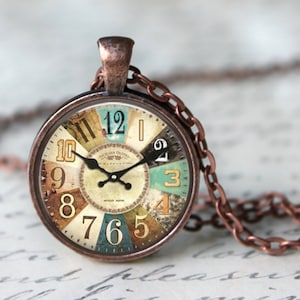 Puede incluir: Un collar de cadena de cobre con un colgante redondo que presenta una esfera de reloj vintage con marcas de números romanos y un diseño colorido y estampado. La esfera del reloj dice "Sicilian Olives" y "Swiss Made".