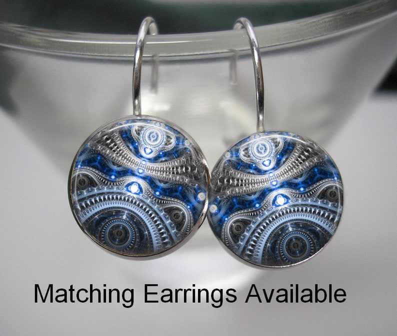 May include: A pair of round, silver-toned earrings with a blue, black, and white abstract design. The earrings have a hook closure. The text "Matching Earrings Available" is displayed below the earrings.