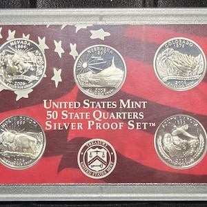 May include: A silver proof set of United States Mint 50 State Quarters. The set includes five quarters, each featuring a different state design, set against a red and white background with stars. The set is encased in a clear plastic holder.