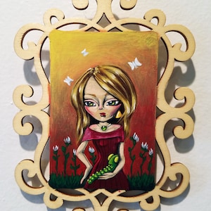 May include: A framed painting of a girl with blonde hair wearing a red dress and holding a green caterpillar. The background is a sunset with white butterflies.