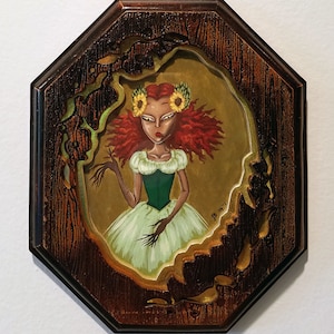 May include: A framed painting of a woman with red hair wearing a green bodice and a white dress. She has a sunflower crown on her head and is holding her hand out. The frame is dark brown wood with a carved design.