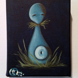 May include: A small, square canvas painting featuring a stylized, blue figure with a round head and a teardrop-shaped body. The figure has closed eyes and a circular design on its torso. It is set against a dark blue background with green grass at the base.