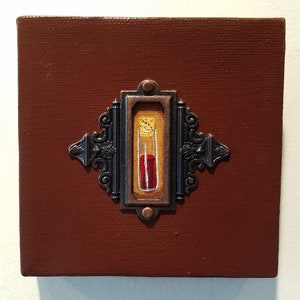May include: A small, framed painting of a glass vial filled with a red liquid. The vial is set against a yellow background and the frame is a dark brown with ornate details.