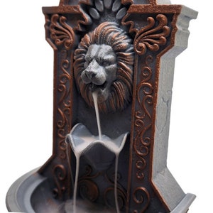 May include: A gray and copper-colored incense burner shaped like a lion's head with ornate details. The incense flows down from the lion's mouth into a basin below.