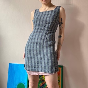 May include: A blue and white plaid sleeveless dress with a square neckline. The dress is fitted and has a short length.