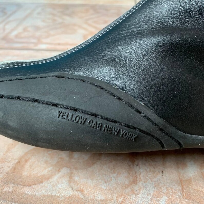 Puede incluir: Primer plano de la suela de cuero negro de un zapato con el texto "YELLOW CAB NEW YORK" impreso en ella.