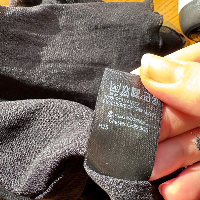 May include: A black garment with a tag that reads "100% Polyamide Exclusive of Trimmings". The tag also includes washing instructions and the Marks and Spencer logo.