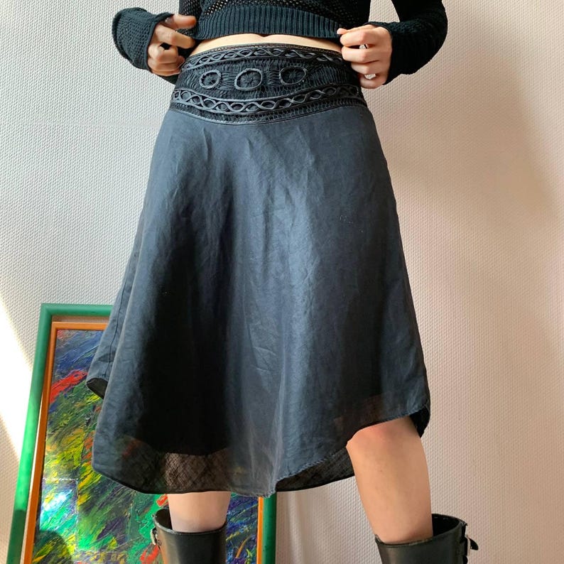 K&ouml;nnte beinhalten: Dunkelblauer Rock mit dekorativem, besticktem Bund. Der Rock hat eine ausgestellte Silhouette und einen transparenten Saum. Der Bund weist ein sich wiederholendes kreisf&ouml;rmiges Muster auf. Der Rock ist aus leichtem Stoff gefertigt.