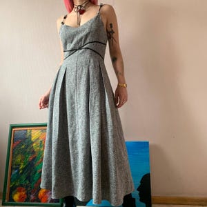 Op de afbeelding: Een grijze en witte geprinte maxi-jurk met zwarte bandjes en een kruisdetail op de buste.