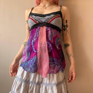 May include: A colorful tank top with a gray bodice, black lace trim, and a vibrant patterned skirt. The skirt features shades of purple, pink, and blue. The top has thin straps and a unique patchwork design.