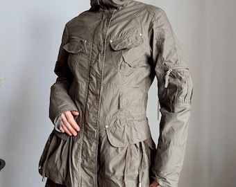 May include: Olive green jacket with a high collar, multiple pockets, and a cinched waist. The jacket features a zipper closure and gathered detailing on the sleeves and lower hem. A stylish outerwear piece.