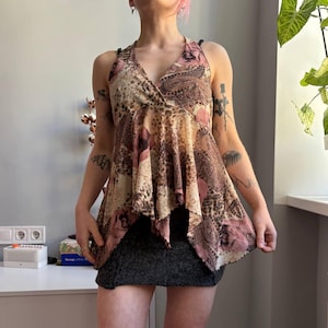 May include: A halter top with a V-neck. The top has a paisley and leopard print in brown, pink, and beige. The outfit is completed with a dark grey skirt.