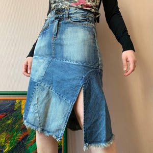 May include: A light blue denim skirt with a patchwork design. The skirt features a front slit and frayed hem. The garment is a mid-length skirt, suitable for casual wear.