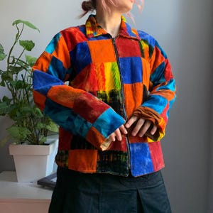 May include: A colorful corduroy jacket with a patchwork design. The jacket features a zipper closure and a collar. The color palette includes vibrant hues of red, orange, blue, and green, creating a bold and eye-catching look.