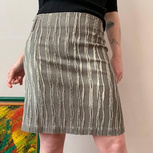 May include: A brown skirt with white vertical stripes. The skirt is made of a textured fabric.
