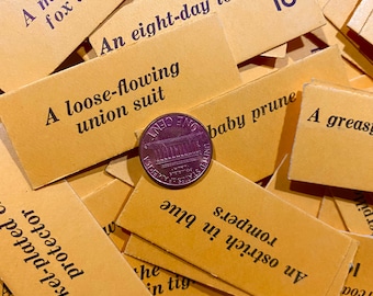 May include: A close-up of a US penny coin on top of a pile of small, yellow index cards with various phrases written on them. The phrases include "A loose-flowing union suit", "An eight-day lollypop", "A nickel-plated protector", and "A greasy baby prune".