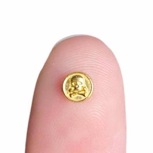 May include: A gold-coloured skull and crossbones charm. The charm is round and has a raised design.