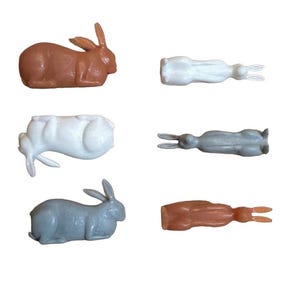May include: Set of six plastic rabbit figurines in various poses. The rabbits are in brown, white, and gray colors.