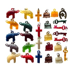 May include: A collection of colorful charms in various shapes, including elephants, crosses, keys, and houses. The charms are in shades of red, yellow, green, blue, and brown, with a metallic loop for attaching to a necklace or bracelet.