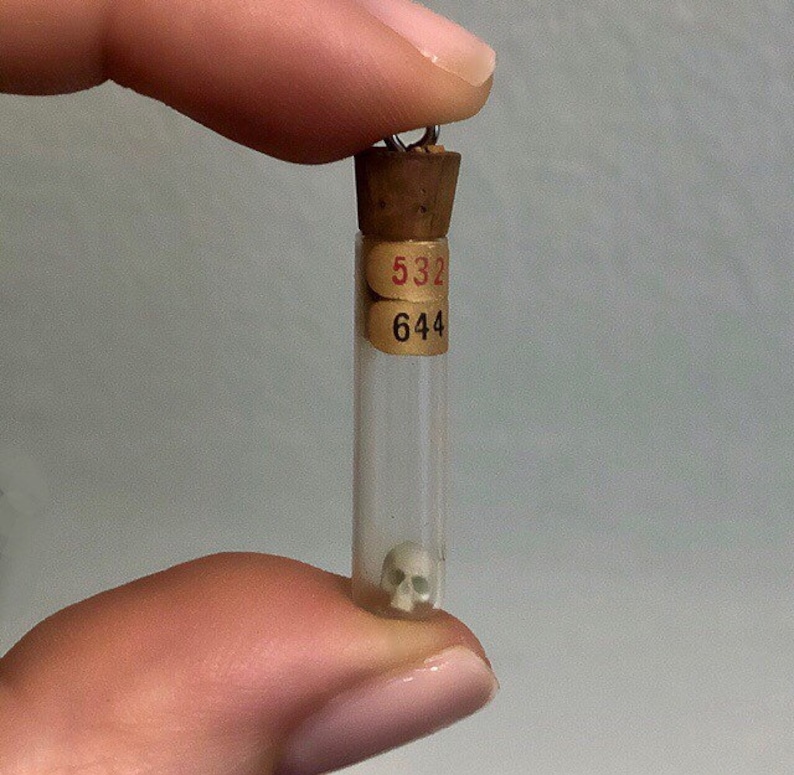 May include: A small glass vial with a cork stopper and a tiny white skull inside. The vial has two labels with the numbers "532" and "644" on them.